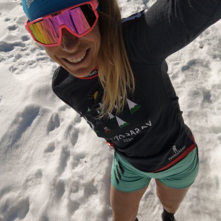 Coureuse blonde sur la neige avec bandeau bleu, lunettes roses et shorty